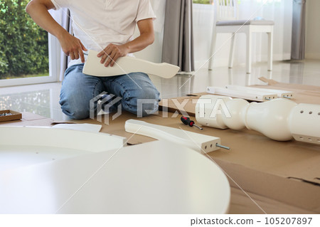 Man assembling white table furniture at home 105207897