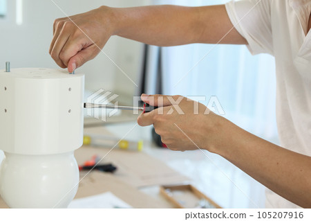Asian man assembling white table furniture at home 105207916