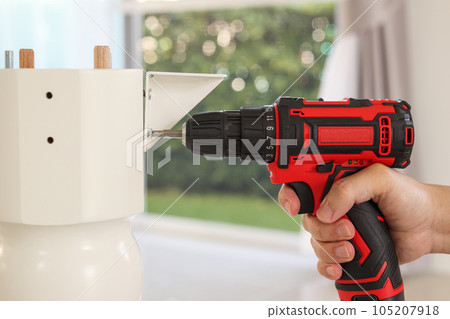 man assembling white table furniture at home using cordless screwdriver man assembling white table furniture at home using cordless screwdriver 105207918