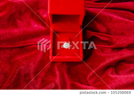 Diamond ring in jewelry gift box on red fabric background 105208069