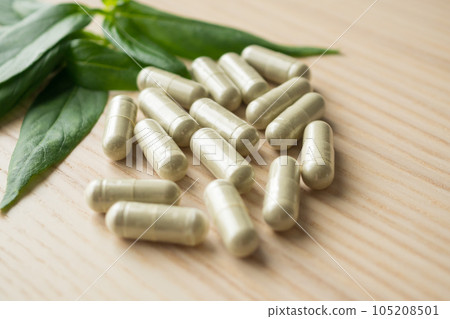 Herbal medicine capsules with Andrographis paniculata leaf on wood table Herbal medicine capsules with Andrographis paniculata leaf on wood table 105208501
