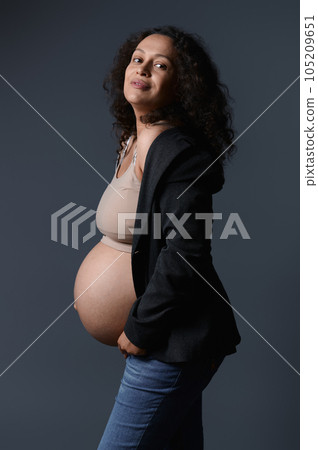 Attractive smiling Latin pregnant woman in stylish blazer, beige bra and blue jeans, showing her naked beautiful belly Attractive smiling Latin pregnant woman in stylish blazer, beige bra and blue jeans, showing her naked beautiful belly 105209651