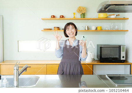 A woman watching a smartphone in the kitchen 105210464