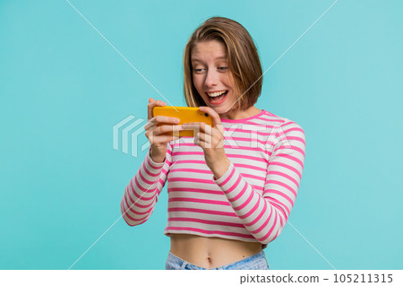 Worried funny addicted tourist girl enthusiastically playing drive racing video game on mobile phone 105211315