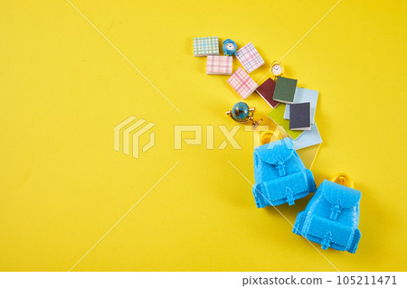 School desk with school accessory and blue backpack on yellow background 105211471