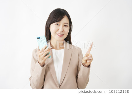 拿著智能手機並且指向正確的白色背景的中年女商人 105212138