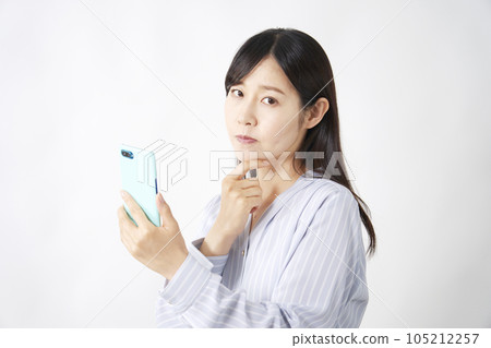 Middle-aged woman thinking with a smartphone Middle-aged woman thinking with a smartphone 105212257