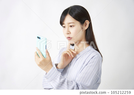 Middle-aged woman thinking with a smartphone Middle-aged woman thinking with a smartphone 105212259
