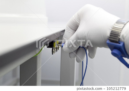 Bracelet on the hand of a man wearing ESD cloth and glove static resistance ESD bracelet or ground equipment, anti-static, used to safely ground is working. Semiconductor manufacturing. Bracelet on the hand of a man wearing ESD cloth and glove static resistance ESD bracelet or ground equipment, anti-static, used to safely ground is working. Semiconductor manufacturing. 105212779