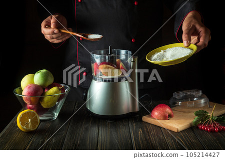 The chef prepares fresh apple juice in an electric blender. The cook adds sugar to the mixer with a spoon. Menu idea for a hotel or restaurant The chef prepares fresh apple juice in an electric blender. The cook adds sugar to the mixer with a spoon. Menu idea for a hotel or restaurant 105214427