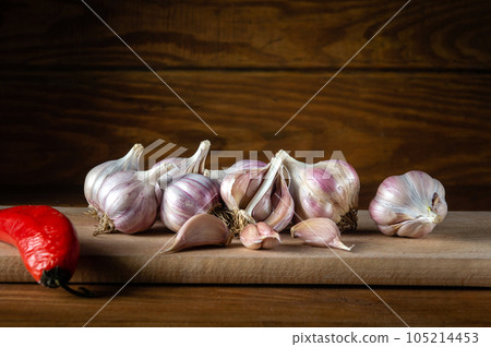 Garlic cloves and red pepper on rustic table. Fresh peeled garlic and bulbs. Copy space for recipe or menu 105214453