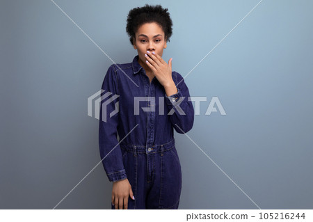 young excited hispanic business woman with fluffy hair dressed in blue denim overalls closed her young excited hispanic business woman with fluffy hair dressed in blue denim overalls closed her 105216244