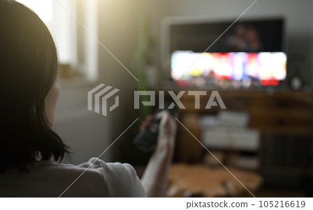 Woman watching television at home and eating chips Woman watching television at home and eating chips 105216619