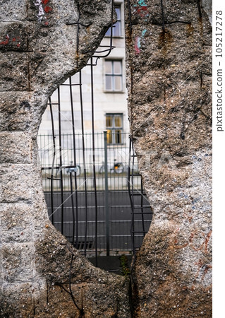 Hole in Broken Berlin wall and walking person against 105217278