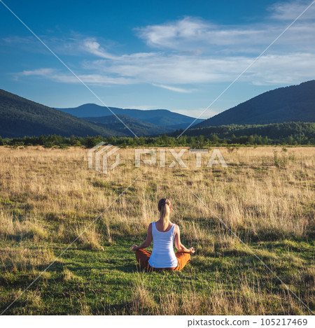 Woman doing yoga on the green grass at the mountain. Carpathians 105217469