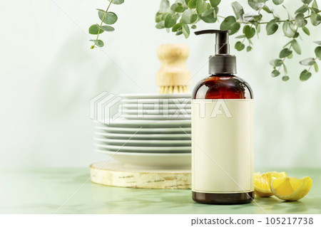 Mockup of natural dish detergent. Eco friendly cleaning dishes. Bottle with dish detergent with clean plates on blue background with lemon slices and sprig of eucalyptus. Front view, copy space 105217738