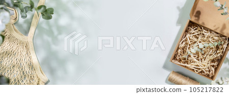 Eco friendly shopping and delivery banner. Environment, sustainable composition with natural textile bag and cardboard box on blue background with green leaves and shadows. Flat lay, copy space 105217822