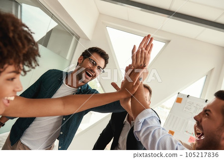 Our success Business people giving each other high-five and smiling while working together in the modern office Our success Business people giving each other high-five and smiling while working together in the modern office 105217836
