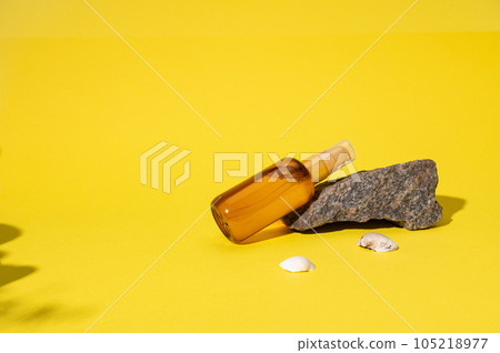 Summer bright layout with bottle of UV protection SPF body oil on a stone. Skincare during sunbathing under sunshine. 105218977