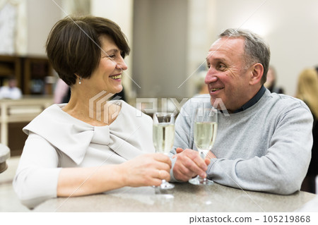 Mature man and woman drinking champagne in theater lobby Mature man and woman drinking champagne in theater lobby 105219868