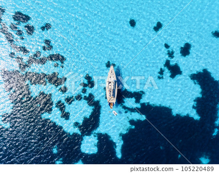 A yacht near the reef. Sail yacht on the sea as a background. Sea and waves from top view. 105220489