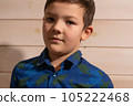 Portrait of a boy 8 years old brunette in a blue shirt. A very serious look. 105222468