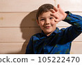 Portrait of a boy 8 years old brunette in a blue shirt. Shows two fingers. 105222470