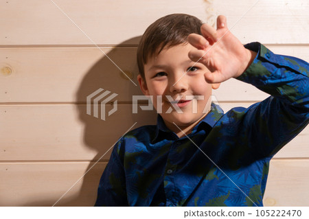 Portrait of a boy 8 years old brunette in a blue shirt. Shows two fingers. 105222470