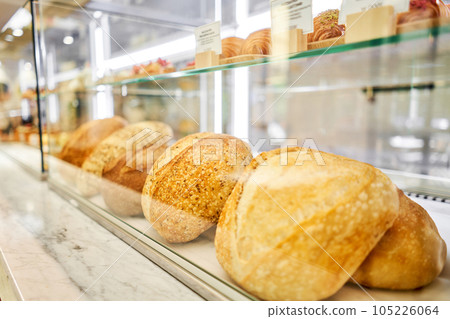 Different kinds of bread on the counter in the bakery shop. Fresh bread counter. Modern bakery with different kinds of bread, cakes and buns Different kinds of bread on the counter in the bakery shop. Fresh bread counter. Modern bakery with different kinds of bread, cakes and buns 105226064