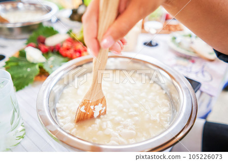 Master class and cheese tasting. Women make cheese. The enzyme and starter culture are added to the milk in a metal container. Milk folding process, home production, business, entrepreneur. 105226073