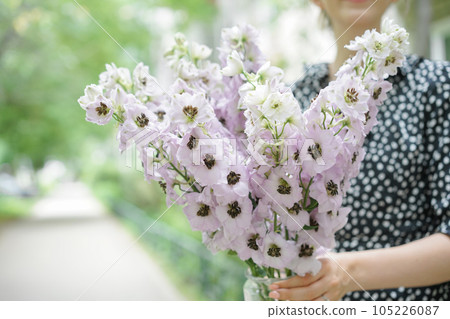 Young girl holding a flower bouquet with Delphiniums of lilac color. Summer wallpaper. Selective focus. Flower shop concept. Young girl holding a flower bouquet with Delphiniums of lilac color. Summer wallpaper. Selective focus. Flower shop concept. 105226087