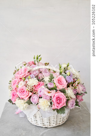Flower arrangement in Wicker basket. Beautiful bouquet of mixed flowers on a marble table. Floral shop concept . Handsome fresh bouquet. Flowers delivery 105226102