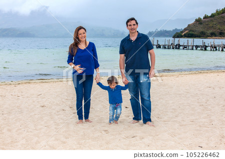 Young couple waiting for their second baby having fun with their baby girl at the beautiful white beach of Lake Tota located in the department of Boyaca at 3,015 meters above sea level in Colombia 105226462