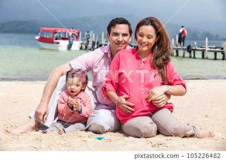 Young couple waiting for their second baby having fun with their baby girl at the beautiful white beach of Lake Tota located in the department of Boyaca at 3,015 meters above sea level in Colombia 105226482