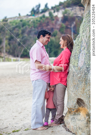 Young couple waiting for their second baby having fun with their baby girl at the beautiful white beach of Lake Tota located in the department of Boyaca at 3,015 meters above sea level in Colombia 105226484