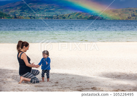 Young pregnant woman having fun with her baby girl at the beautiful white beach of Lake Tota located in the department of Boyaca at 3,015 meters above sea level in Colombia Young pregnant woman having fun with her baby girl at the beautiful white beach of Lake Tota located in the department of Boyaca at 3,015 meters above sea level in Colombia 105226495