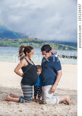 Young couple waiting for their second baby having fun with their baby girl at the beautiful white beach of Lake Tota located in the department of Boyaca at 3,015 meters above sea level in Colombia Young couple waiting for their second baby having fun with their baby girl at the beautiful white beach of Lake Tota located in the department of Boyaca at 3,015 meters above sea level in Colombia 105226497