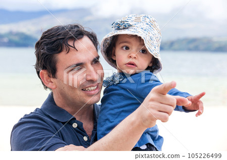 Young father having fun with his baby girl at the beautiful white beach of Lake Tota located in the department of Boyaca at 3,015 meters above sea level in Colombia 105226499