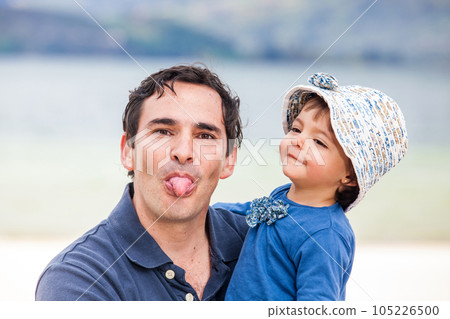 Young father having fun with his baby girl at the beautiful white beach of Lake Tota located in the department of Boyaca at 3,015 meters above sea level in Colombia 105226500