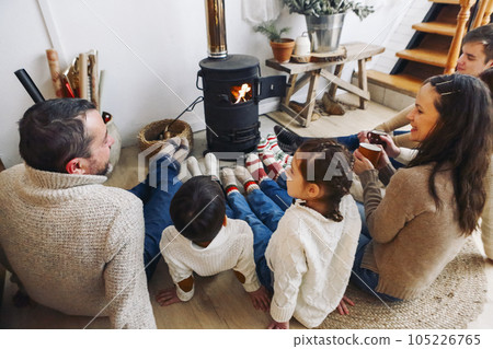 Cropped photo of big family wearing warm woolen socks resting by fireplace together in winter time 105226765