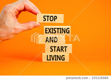 Stop existing start living symbol. Concept words Stop existing and start living on wooden blocks. Beautiful orange table orange background. Business Stop existing start living concept. Copy space. Stop existing start living symbol. Concept words Stop existing and start living on wooden blocks. Beautiful orange table orange background. Business Stop existing start living concept. Copy space. 105226866