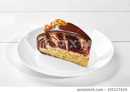 Slice of chocolate and vanilla sponge cake with ganache and caramelized walnuts Slice of chocolate and vanilla sponge cake with ganache and caramelized walnuts 105227429