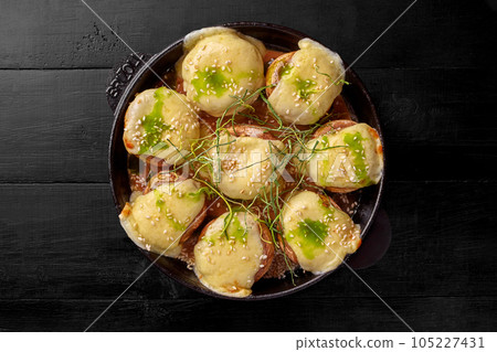 Baked champignons stuffed with suluguni sprinkled with fried green onions 105227431