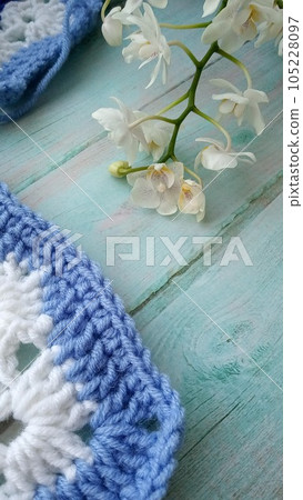 Blue, white crochet elements and orchid. Crochet texture, place for an inscription, adapted for mobile phone Blue, white crochet elements and orchid. Crochet texture, place for an inscription, adapted for mobile phone 105228097