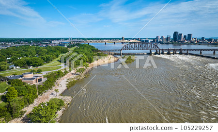 Aerial summer shoreline with distant brown arch bridge over Ohio River dam Louisville Kentucky Aerial summer shoreline with distant brown arch bridge over Ohio River dam Louisville Kentucky 105229257