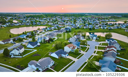 Aerial sunset sunrise over suburban houses neighborhood with four ponds cul-de-sac green lawns 105229306