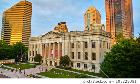 Green lawn with flags outside Capital Square Foundation at sunrise with sun on skyscrapers aerial Green lawn with flags outside Capital Square Foundation at sunrise with sun on skyscrapers aerial 105229381
