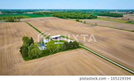 Aerial clean farmhouse landscape property aerial with green runoff ditches, paved road, empty fields 105229394