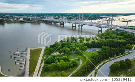 White truss, suspension bridges with rusty arch bridge on Ohio River near docks and greenery aerial 105229411