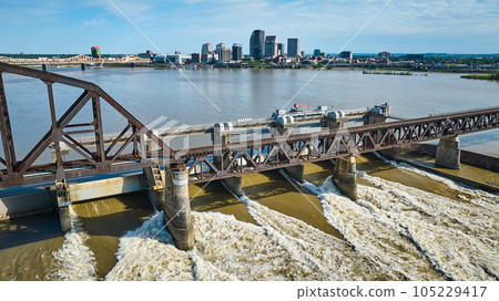 Aerial brown truss arch bridge over dam in Ohio River white water rapids Louisville city skyline Aerial brown truss arch bridge over dam in Ohio River white water rapids Louisville city skyline 105229417